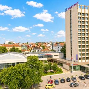a large building with cars parked in a parking lot at Hotel Rostov in Pleven