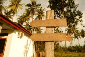 a wooden sign in front of a house with palm trees at FaqinHomestay in Pulau Sarang +6 photos