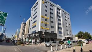 a large white building on a city street with cars at أجنادين للشقق المخدومة in Riyadh