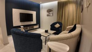 a living room with two chairs and a table and a tv at أجنادين للشقق المخدومة in Riyadh