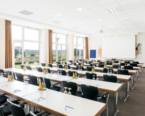 a lecture room with tables and chairs and a whiteboard at PLAZA INN Hamburg Horner Rennbahn in Hamburg