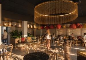 a woman walking through a restaurant with a chandelier at Ysotop Hôtel Grenoble in Grenoble