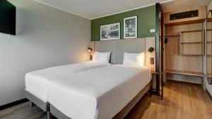 a large white bed in a room with green walls at Campanile NATURE - Metz Technopôle in Metz