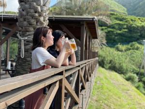 two women sitting on a balcony drinking beer at スパイス平戸 in Hirado