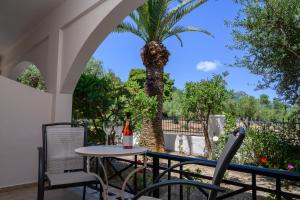 a table and chairs on a patio with a palm tree at Olga Studios in Vasilikos
