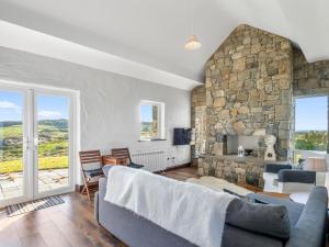a living room with a couch and a stone wall at Paddy Carrolls Cottage in Ballyconneely