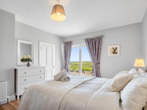 a white bedroom with a bed and a window at Paddy Carrolls Cottage in Ballyconneely