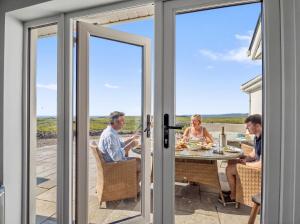 a group of people sitting at a table in front of doors at Paddy Carrolls Cottage in Ballyconneely