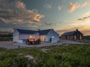 a group of people sitting around a table in front of a house at Paddy Carrolls Cottage in Ballyconneely