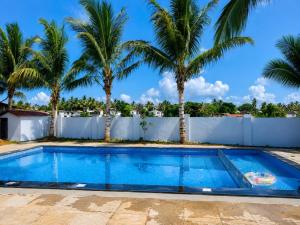 a swimming pool with palm trees in the background at Golden Pearl Beach Resort in Baga