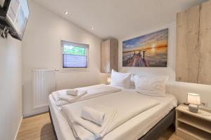 a bedroom with a large white bed in a room at Ferienhaus "Ostseeperle" mit kostenfreier Saunanutzung, Grundstück Umzäunt in Scharbeutz