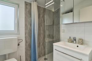 a white bathroom with a sink and a shower at Ferienhaus "Ostseeperle" mit kostenfreier Saunanutzung, Grundstück Umzäunt in Scharbeutz