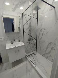 a white bathroom with a shower and a sink at Tina's home in Batumi +5 photos