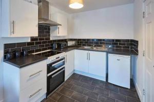 a kitchen with white cabinets and a black tile floor at Skinningrove Beach House 1 in Skinningrove
