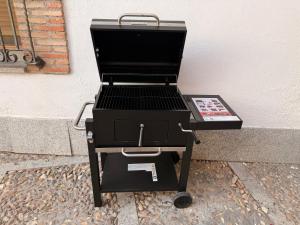a barbecue grill sitting on a sidewalk next to a wall at Casa Dorrego Toledo in Cabañas de la Sagra