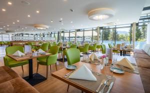 a restaurant with wooden tables and green chairs at Hotel Grimmingblick GesmbH in Bad Mitterndorf
