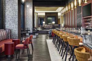 a lobby with a bar with chairs and a couch at Apiary Hotel Belleview Station Denver in Denver