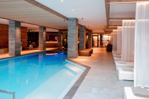 une grande piscine dans le hall de l'hôtel dans l'établissement Hotel Piz Buin Klosters, à Klosters