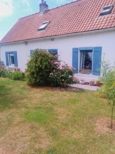 a white house with blue windows and a yard at La Détente in Rinxent