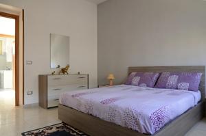 ノートにあるCasa Nonna Saraのベッドルーム1室(紫色の枕とドレッサー付きのベッド1台付)