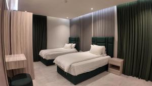 two beds in a room with black curtains at أجنادين للشقق المخدومة in Riyadh