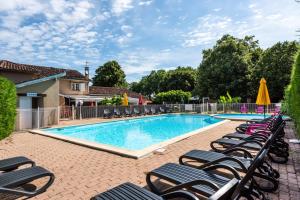 a swimming pool with chaise lounges and chairs at Chalet paisible in Rivières