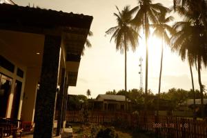 a group of palm trees in front of a building at FaqinHomestay in Pulau Sarang