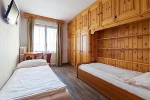 two beds in a room with wooden walls at Hotel Aquila in Cortina dʼAmpezzo