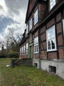 an old brick building with a green door and windows at Altes Gutshaus Schwiessel in Prebberede