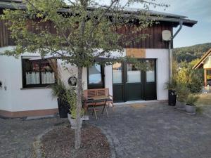 a tree in front of a house with a bench at Ferienwohnung Zum Eifelelch in Daun