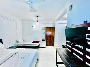 a white bedroom with a bed and a tv at Beachside Studio Apartment Baga in Baga