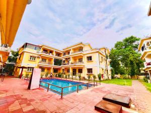 a large building with a swimming pool in front of it at Beachside Studio Apartment Baga in Baga