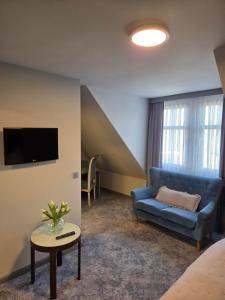 a living room with a blue couch and a tv at Hotel zur Kaiserpfalz in Kaiserpfalz