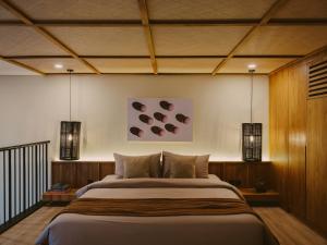 a bedroom with a large bed and two lights at Anandaya Sanur in Sanur