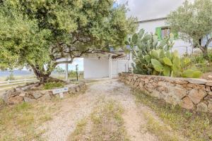 a white garage with a tree and a stone wall at Rai's Private Apt 3 - Panorama & Relax in Stazione Olbia +9 photos
