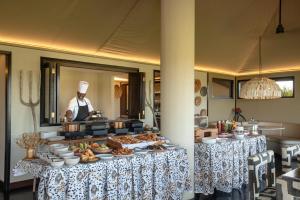 a chef is standing behind a buffet of food at Mahali Mzuri in Aitong