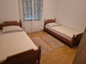 two twin beds in a room with a window at Apartman Pecara in Široki Brijeg