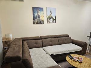 a living room with a brown couch and three pictures on the wall at Elena Residence 15min from Belgrade in Pančevo