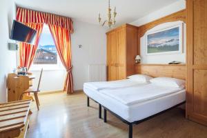 a bedroom with a bed and a table and a tv at Hotel Aquila in Cortina dʼAmpezzo