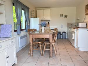 a kitchen with a table and chairs and a refrigerator at Daisy Cottage with seasonal Swimming Pool in Le Mesnil-Gilbert