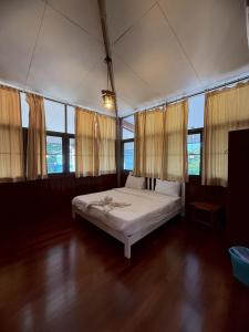 a bedroom with a bed in a room with windows at Bann Maii Soi 14 in Ban Hua Khao Sammuk