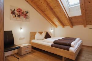 a bedroom with a bed and a chair at Appartementhaus Söllbacherhof in Fügen