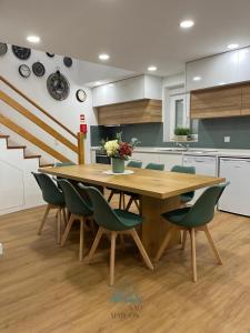 a kitchen with a wooden table and green chairs at Quintal de São Marcos in Castelo Branco