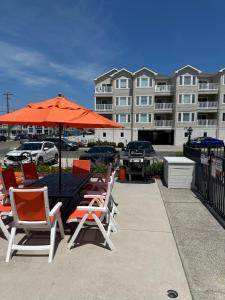 a table and chairs with an orange umbrella at Sea Chest Motel in Wildwood Crest