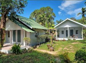 a small white house with a green roof at Wave & Vibes Koh chang in Ban Chek Bae (1)