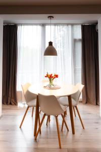 a dining room table with white chairs and a vase of flowers at Alexa Apartament in Târgu-Mureş