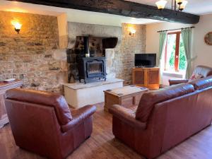 a living room with leather furniture and a fireplace at Daisy Cottage with seasonal Swimming Pool in Le Mesnil-Gilbert