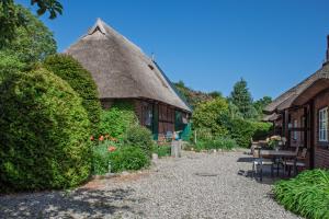 a cottage with a thatch roof and a table and chairs at Reethaus Beusloe I in Beusloe