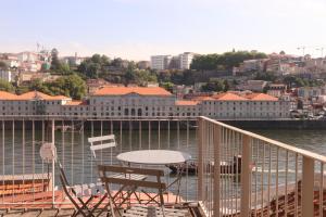 a table and chairs on a balcony overlooking the water at Gaia River View in Vila Nova de Gaia