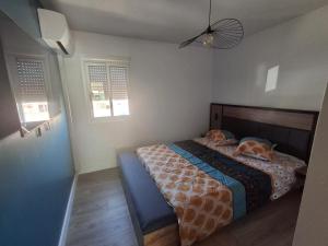a bedroom with a bed and two windows at Résidence soleilla in Le Barcarès
